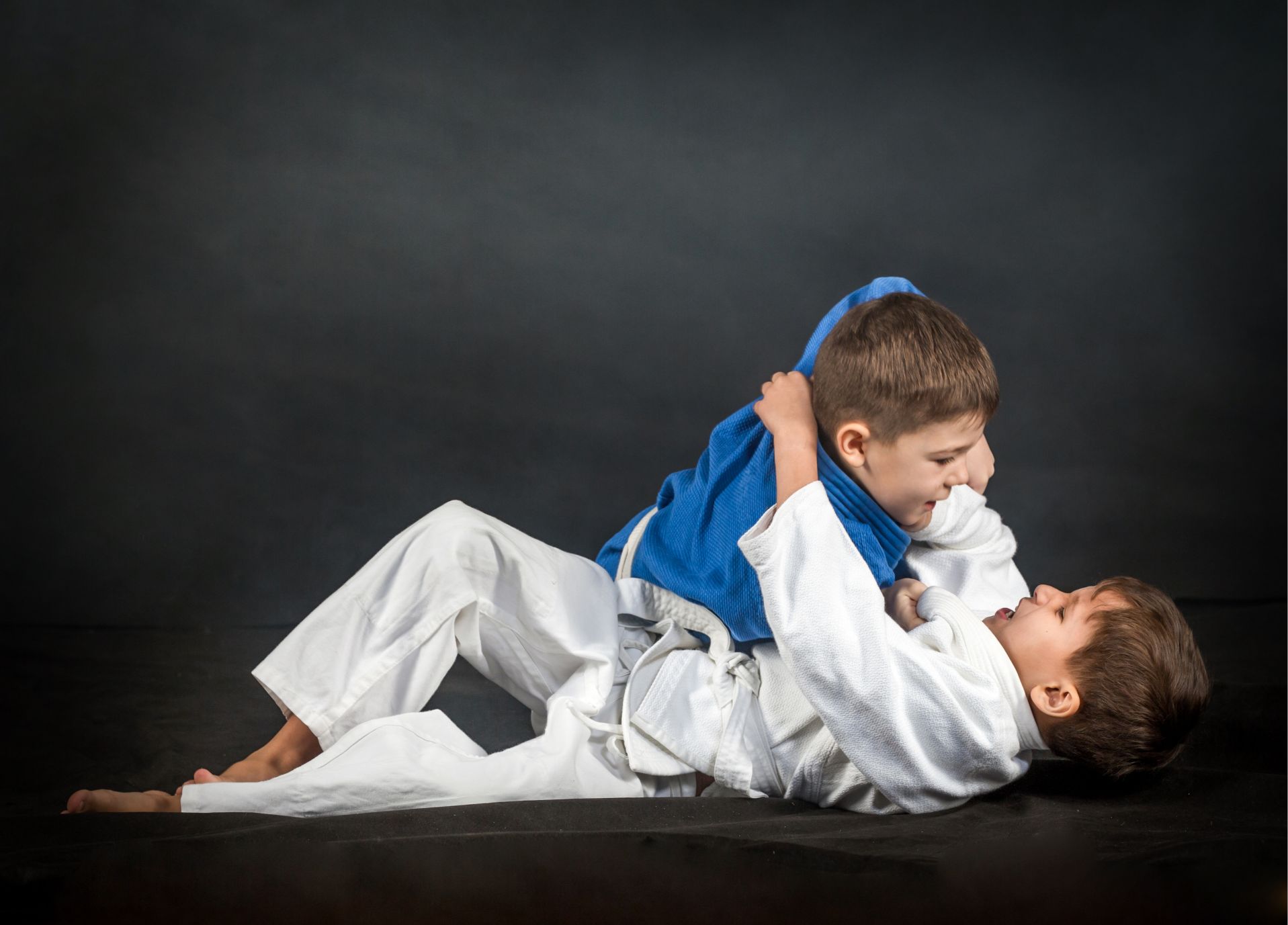 Two children practicing BJJ on a mat