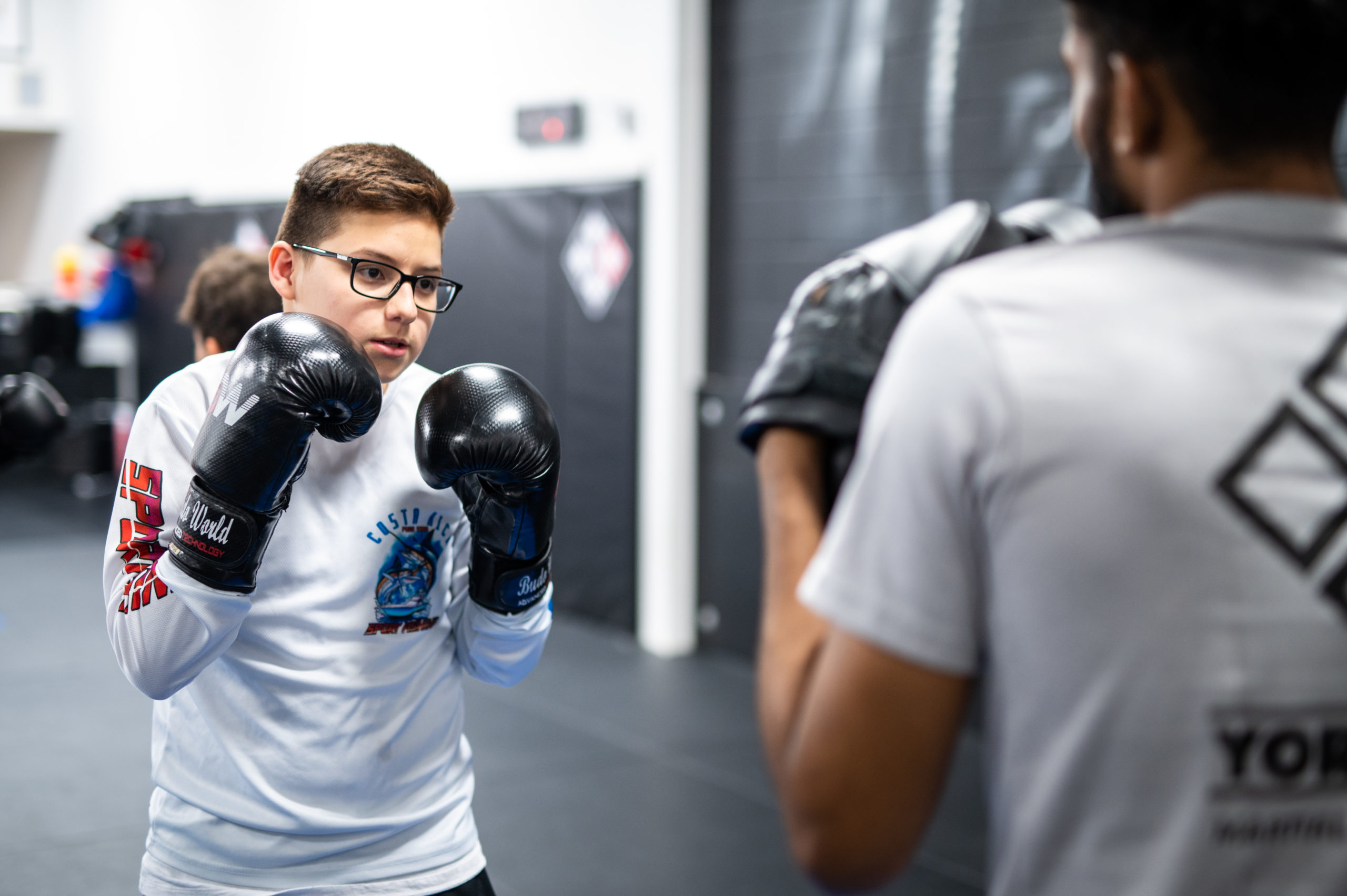 Yorkdale Martial Arts trainer shows Teen Muay Thai student new drills.