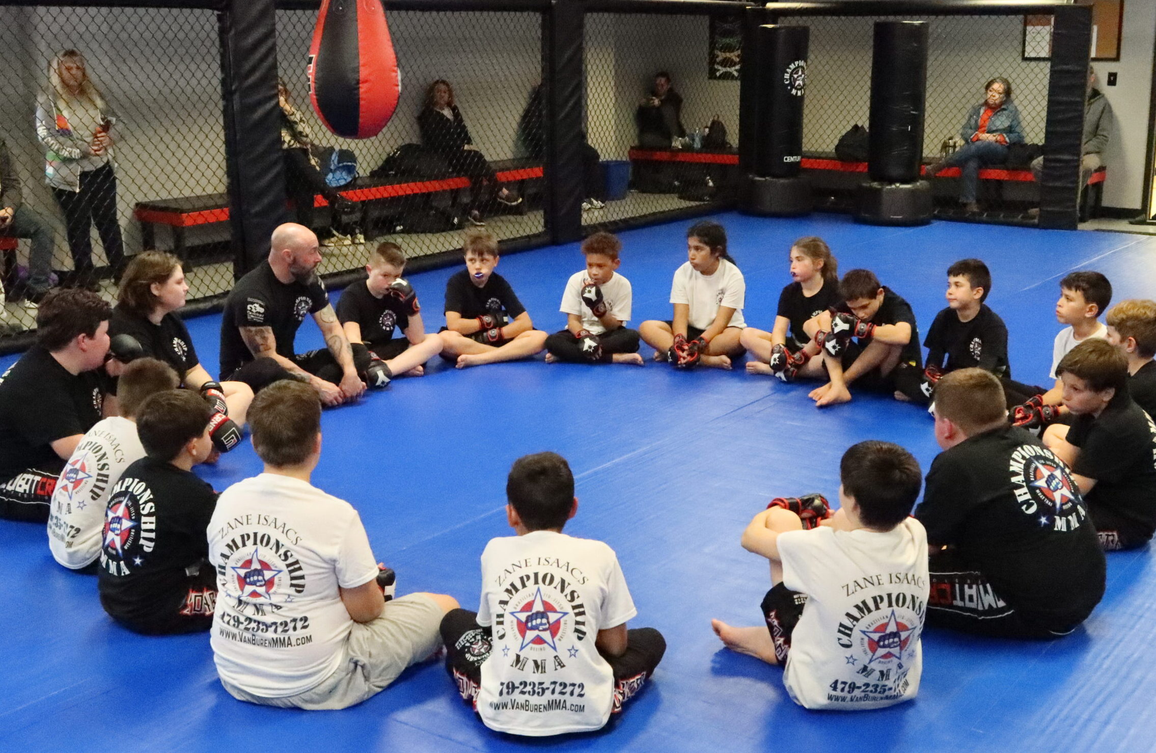 Youth MMA students sitting in a circle with Coach Zane at Championship MMA